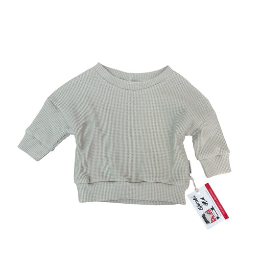 Light gray ribbed sweater with a tag on a white background